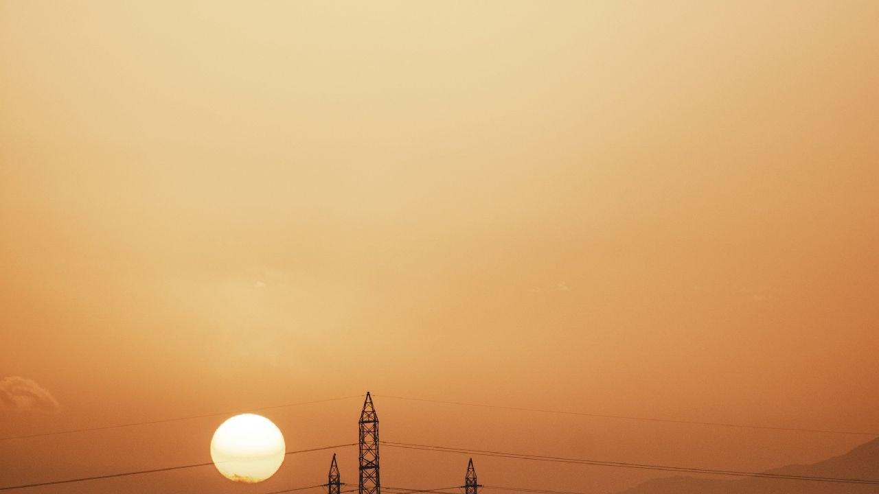 Power lines silhouetted against a hazy sunset